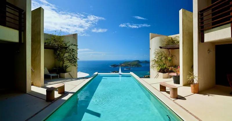 Artist’s rendering of a long lap pool running between walls toward the sea and a distant island