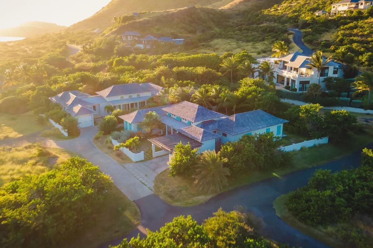 Artist’s rendering of villas set along a green hillside above a bay, seen from the air