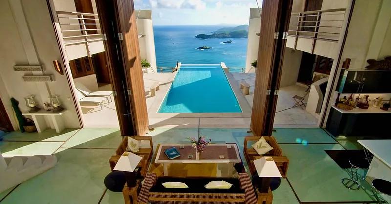 An open living space looking down over a pool to the sea and islands
