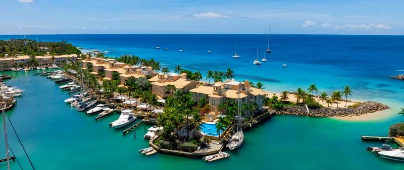 A marina with moored boats beside a resort on the Barbados coast, seen from the air