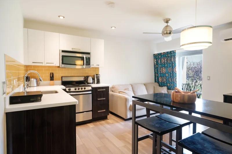 A compact kitchen and living area with a breakfast bar and stools