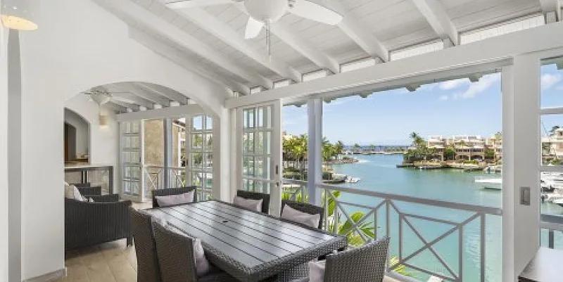A covered terrace with a dining table looking out over a marina lagoon