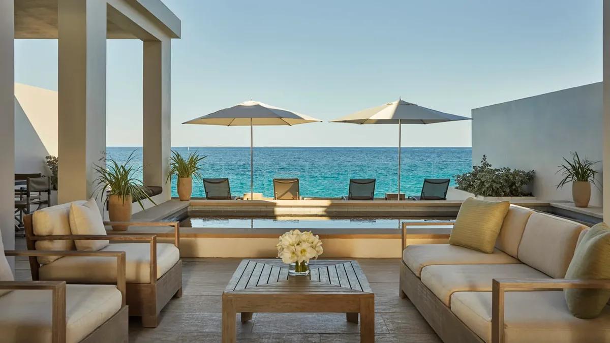 A shaded terrace lounge with deep sofas and parasols looking out to the sea