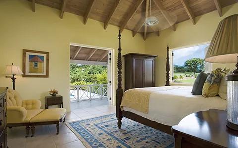 A yellow bedroom with a mahogany four-poster bed under a vaulted timber ceiling