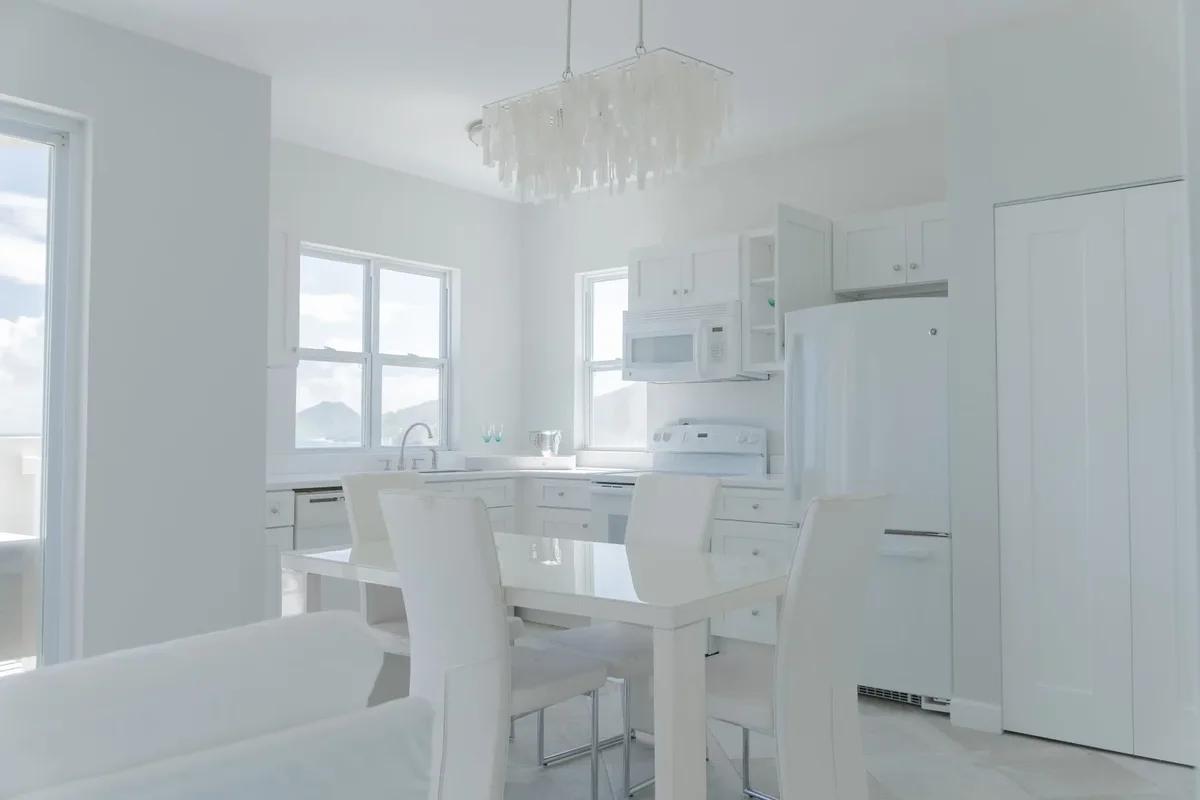 A white kitchen and dining area with a glass chandelier over the table