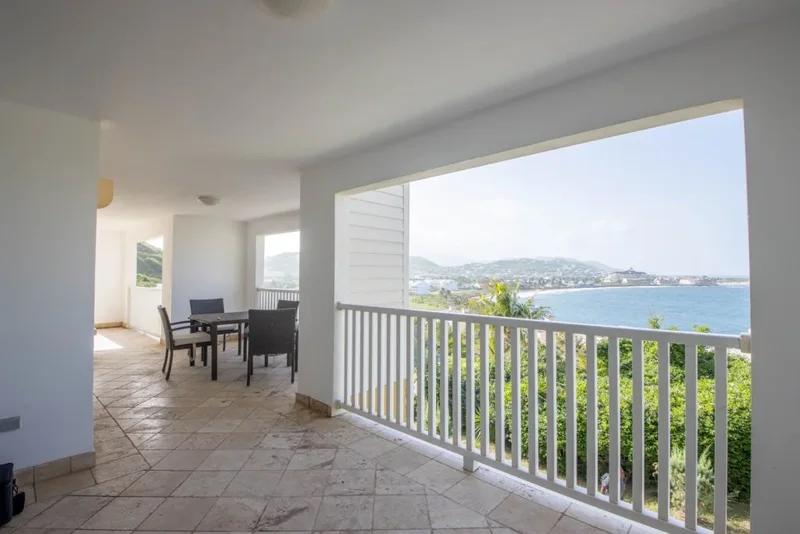 An empty tiled room opening onto a balcony above the sea