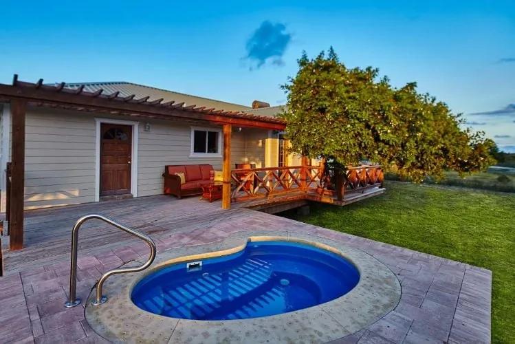 A small kidney-shaped pool on a paved terrace beside a timber deck and lawn