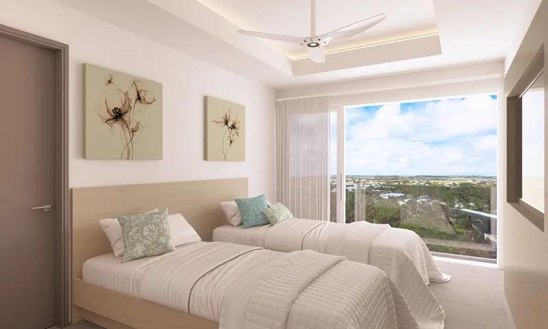A twin bedroom under a ceiling fan with framed botanical prints and a window to the coast