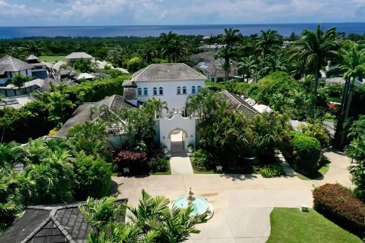 A villa at Royal Westmoreland, Barbados, seen from the air among palms and mature gardens with its pool below