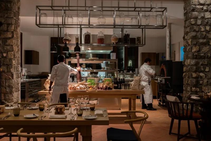 A restaurant with a stone wall and open kitchen, chefs working behind the counter