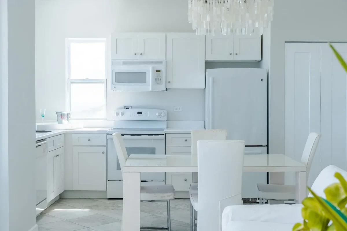 A compact white kitchen with a small dining table and chairs
