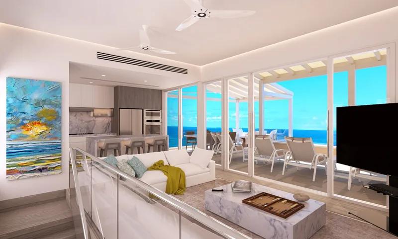 A living room with a backgammon table and a large television, opening to a terrace above the sea