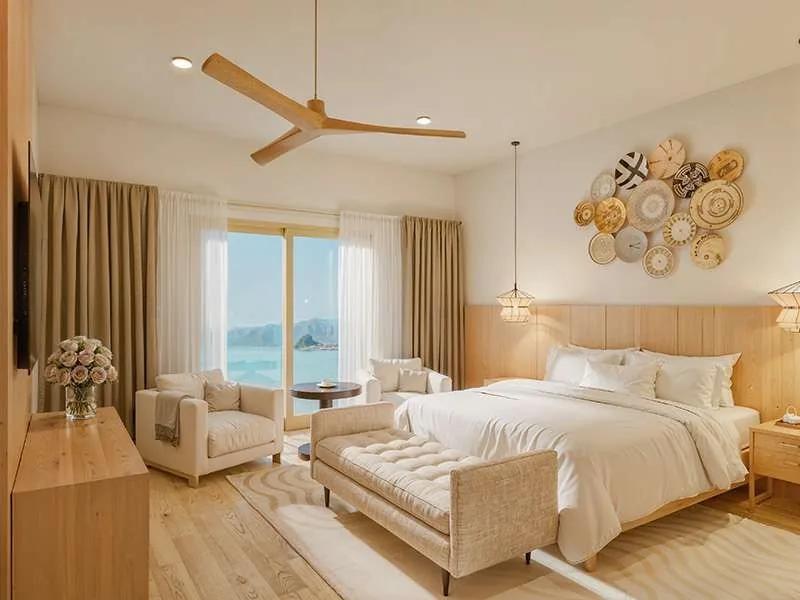 A bedroom with a timber ceiling fan, a cluster of woven wall discs and a bench at the foot of the bed