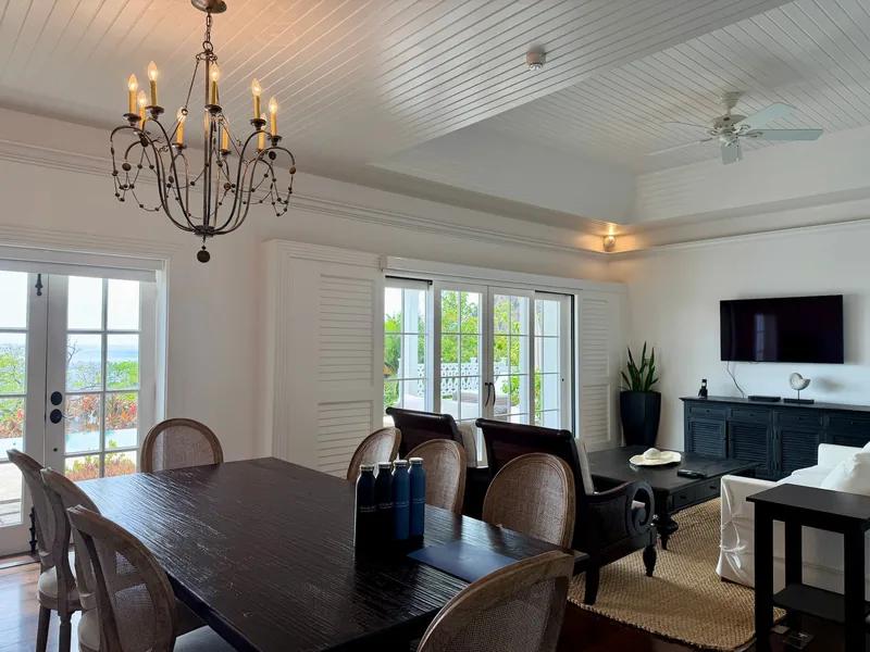 A white dining room with a wrought-iron chandelier and French doors to the terrace