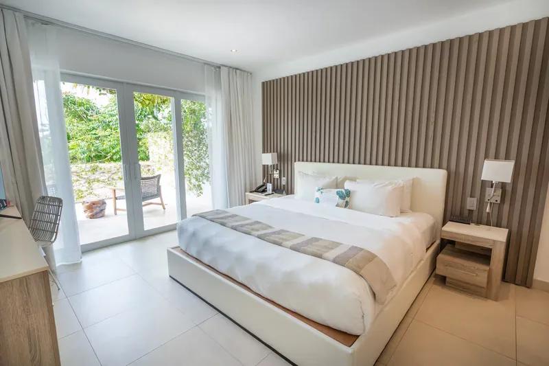 A bedroom with a slatted timber feature wall and glass doors onto a garden