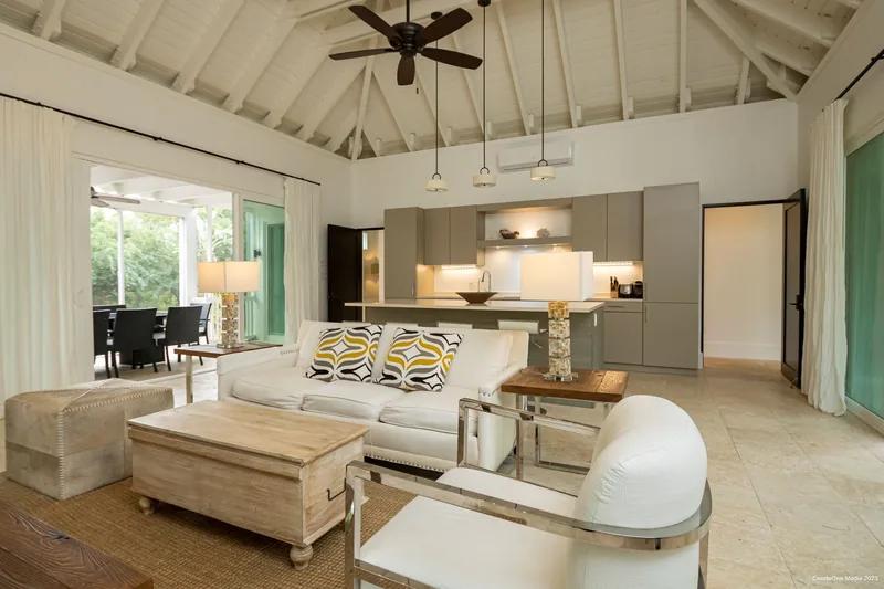 A living room under a white vaulted ceiling, sofas facing a dining area beyond