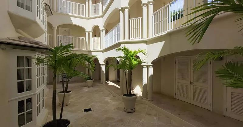 A shaded courtyard with arched balconies and potted palms