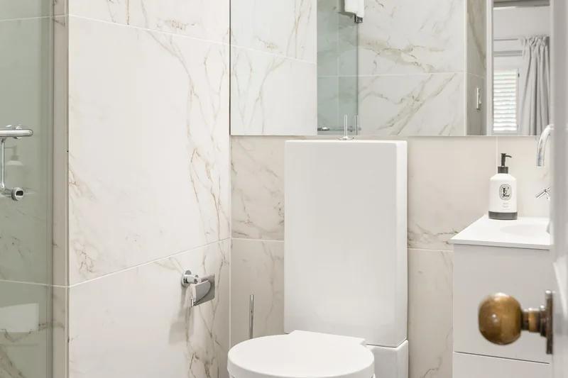 A marble-lined bathroom with a glass shower screen and wall-mounted fittings