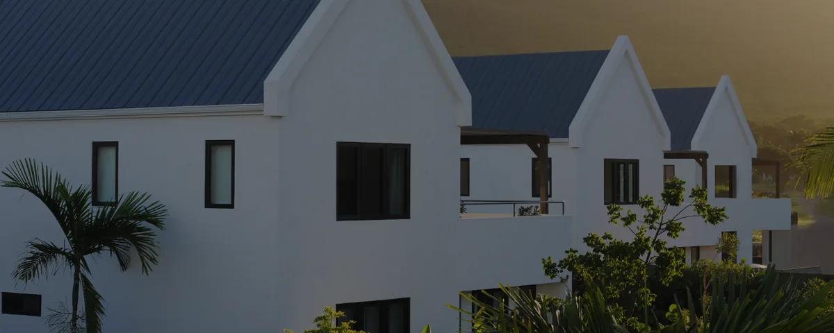 White gabled villas with dark shingle roofs standing among palms