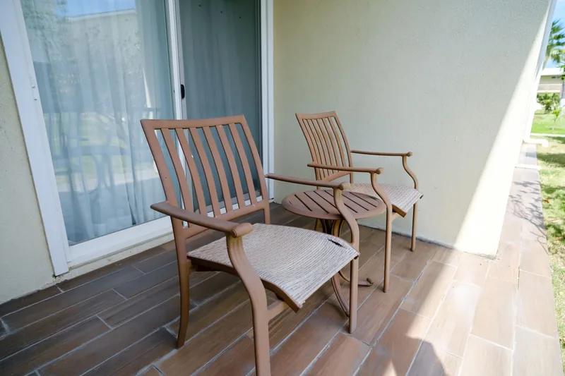 Two timber armchairs with a footstool on a small tiled balcony