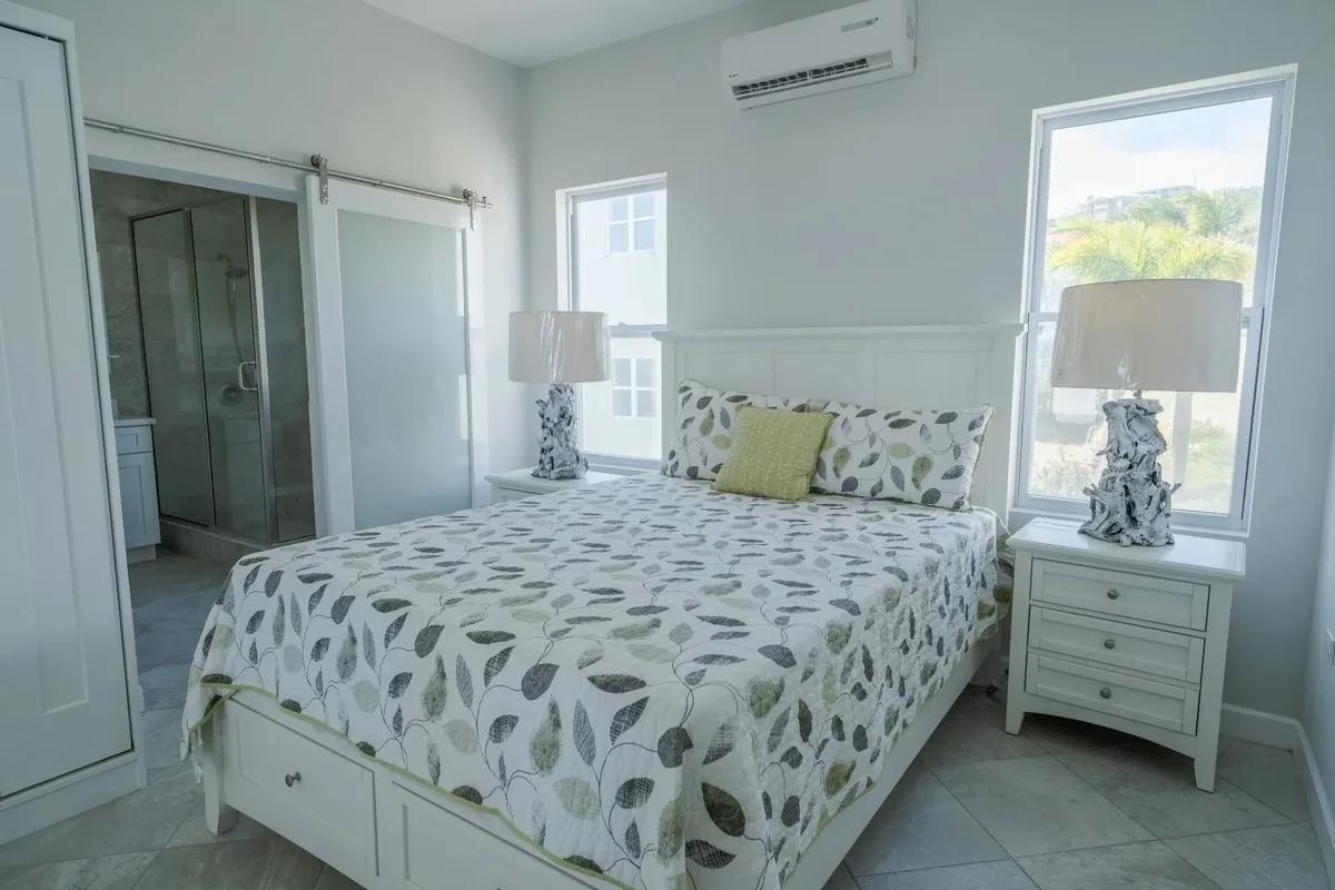 A bedroom with a leaf-patterned bedspread, matching lamps and a sliding barn door