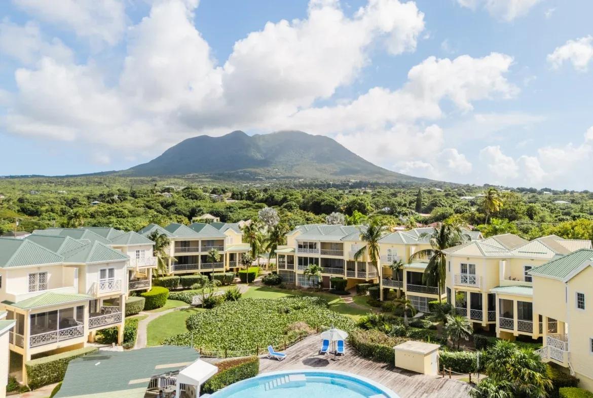 Pastel condominium buildings below Nevis Peak, a pool in the foreground