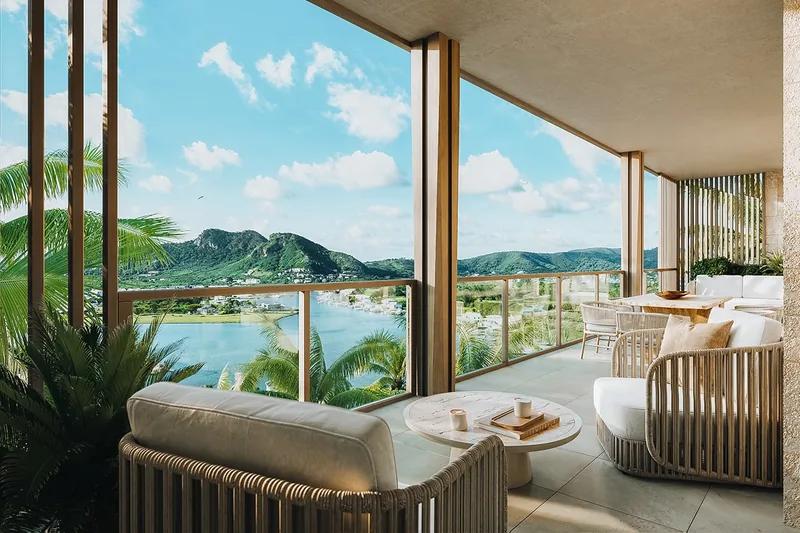 A covered terrace with rattan seating looking across a lagoon to green hills