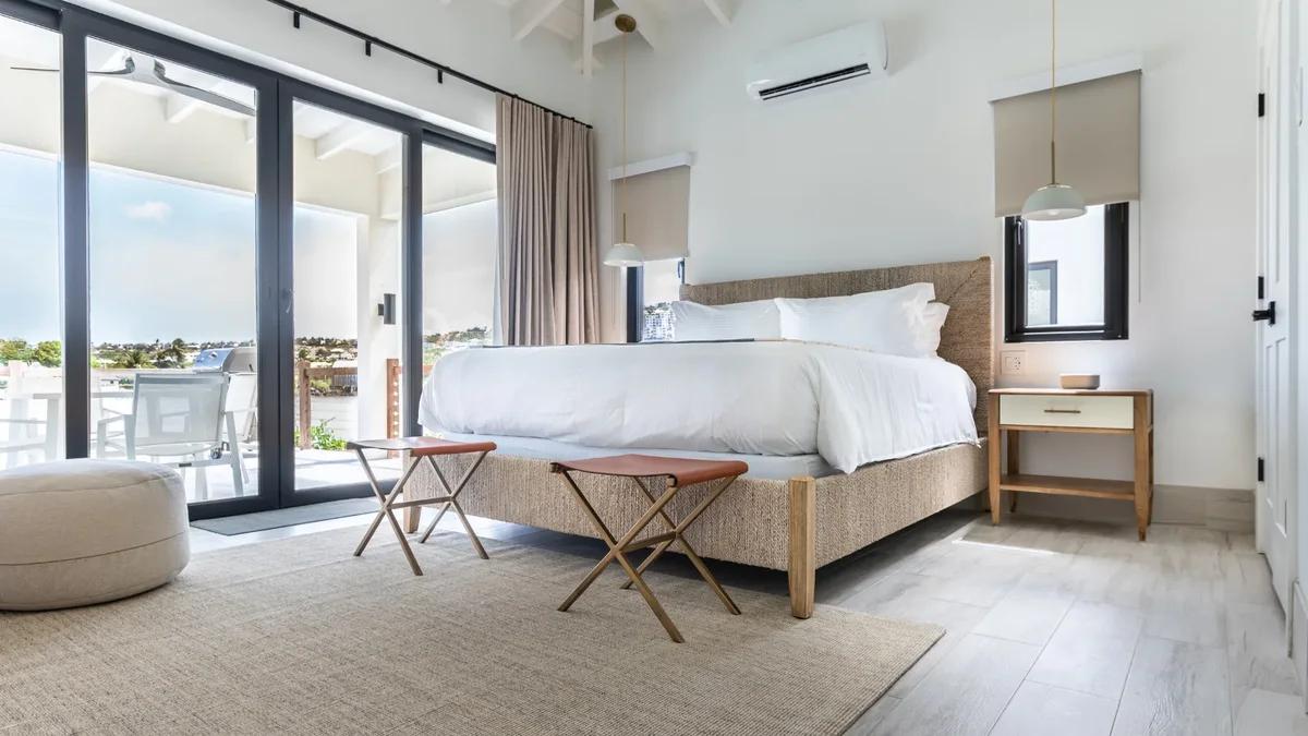 A bedroom with a pale timber bed and sliding doors opening to a balcony