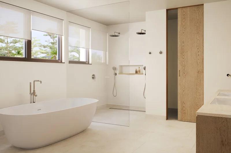 A white bathroom with a freestanding bath, a walk-in shower and clerestory windows