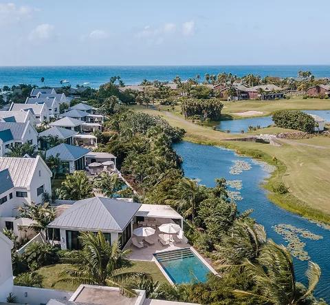 White-roofed villas among palms beside a lagoon, the sea beyond