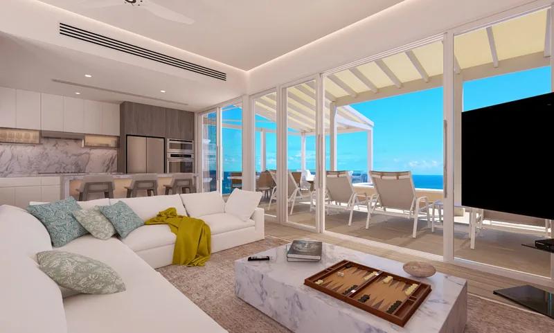 A living room with white sofas and a backgammon board, opening to a terrace above the sea