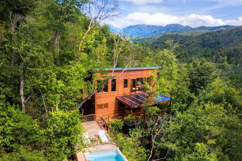 A timber villa on a forested ridge in Dominica, mountains behind