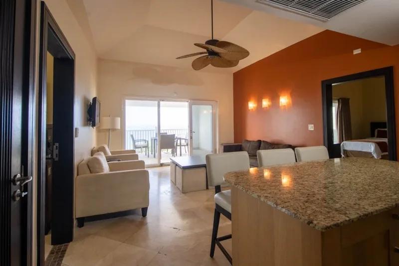 An apartment interior with a ceiling fan, an orange accent wall and a granite kitchen island